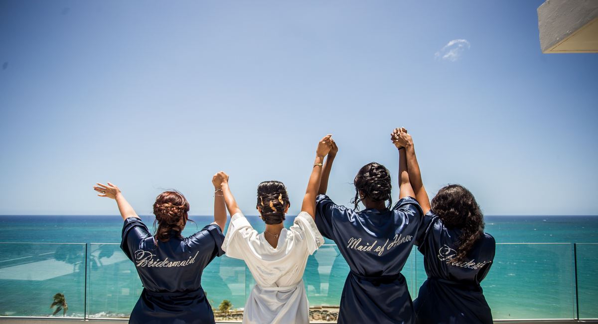 A bridal party with their hands in the air